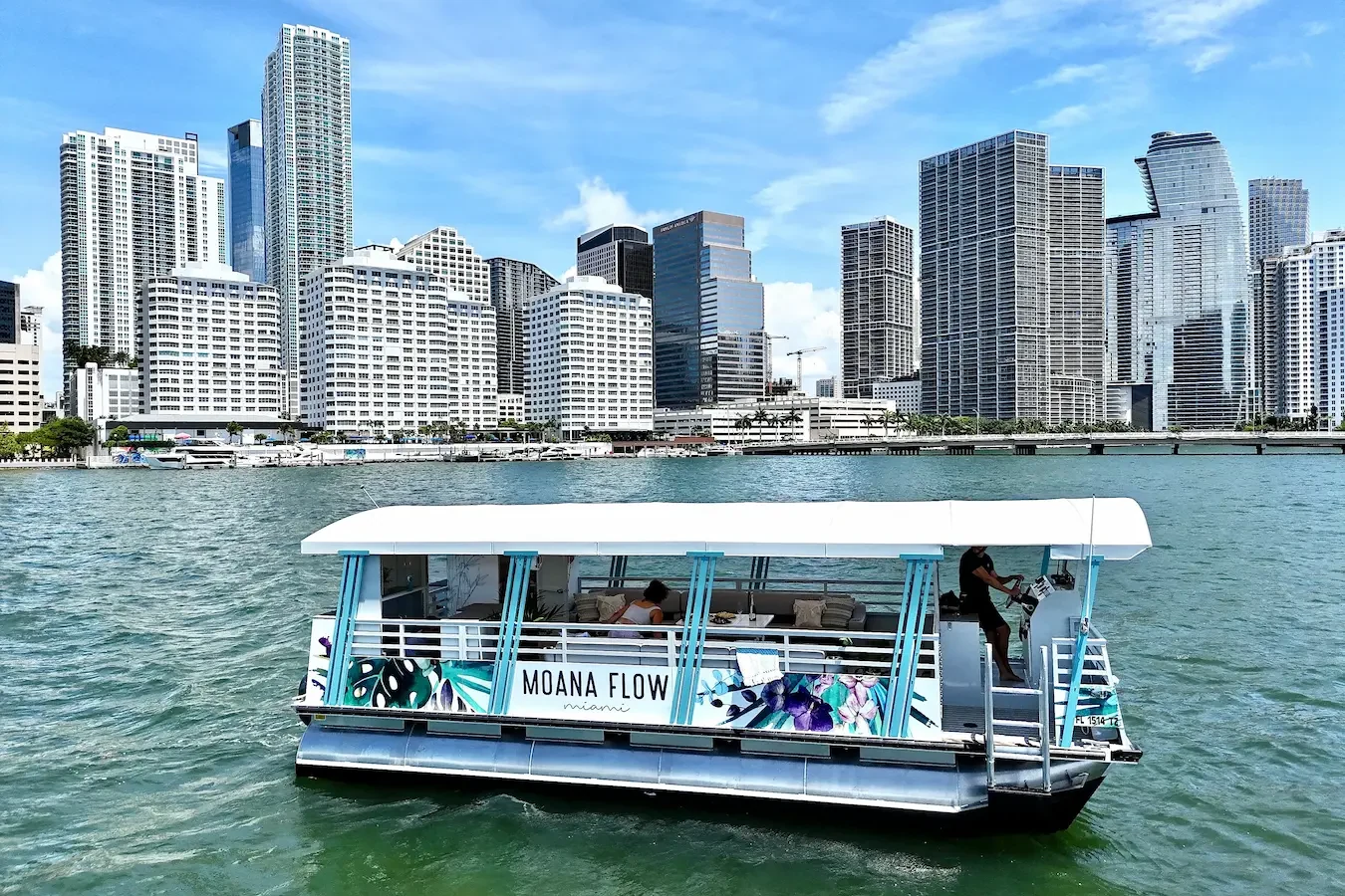 Boho-styled pontoon charter boat on the water with the Miami skyline behind